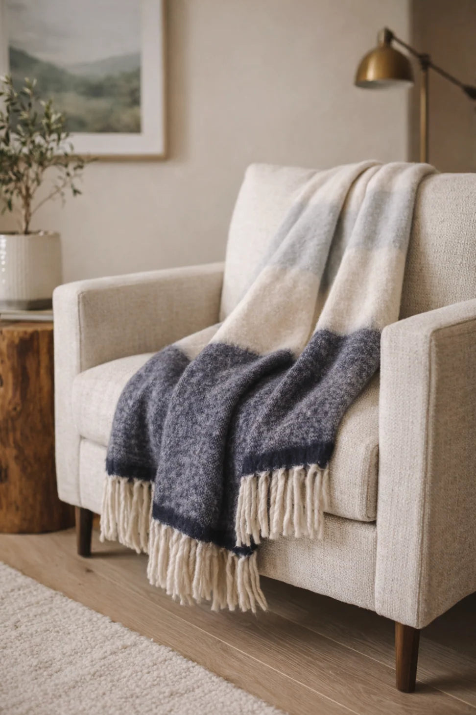 Cream armchair with POM POM Whistler Throw in a softly lit cozy living room, Bungalow Furniture & Accessories.