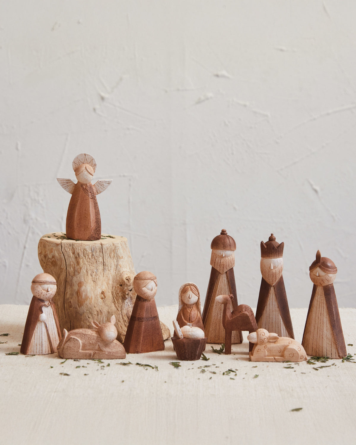 Minimalist nativity set featuring the holy family, an angel, wise men, and animals with a natural wood finish.