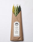 The Woodland Spiral Beeswax Candles S/4 by Faire are hand-crafted in yellow and green with natural dye, wrapped in brown paper, and labeled “handmade with local beeswax, Hudson Valley, NY.”.