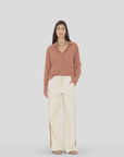 Xirena Bradshaw Pant styled with a brown button-up shirt and tan shoes, set against a light gray background.