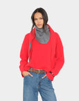 Le Petit Scarf in red, styled with a cozy sweater and jeans; modern casual look, neutral background.