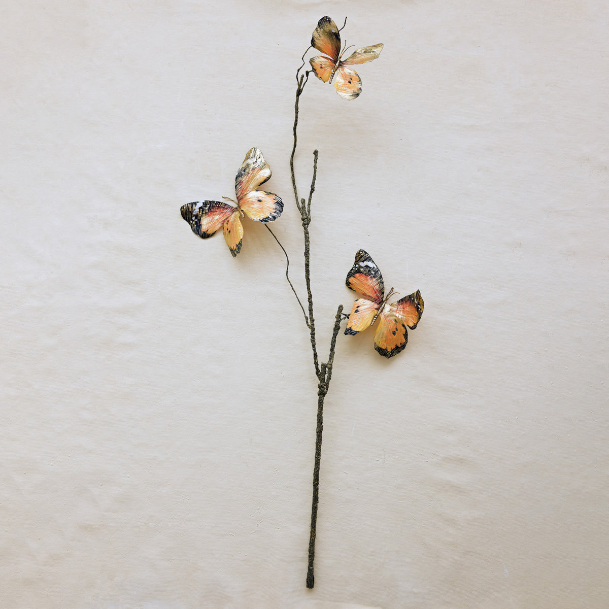 Three orange and black butterflies on a thin stem, Creative Co-op XT1539 Butterfly Stem, beige background.