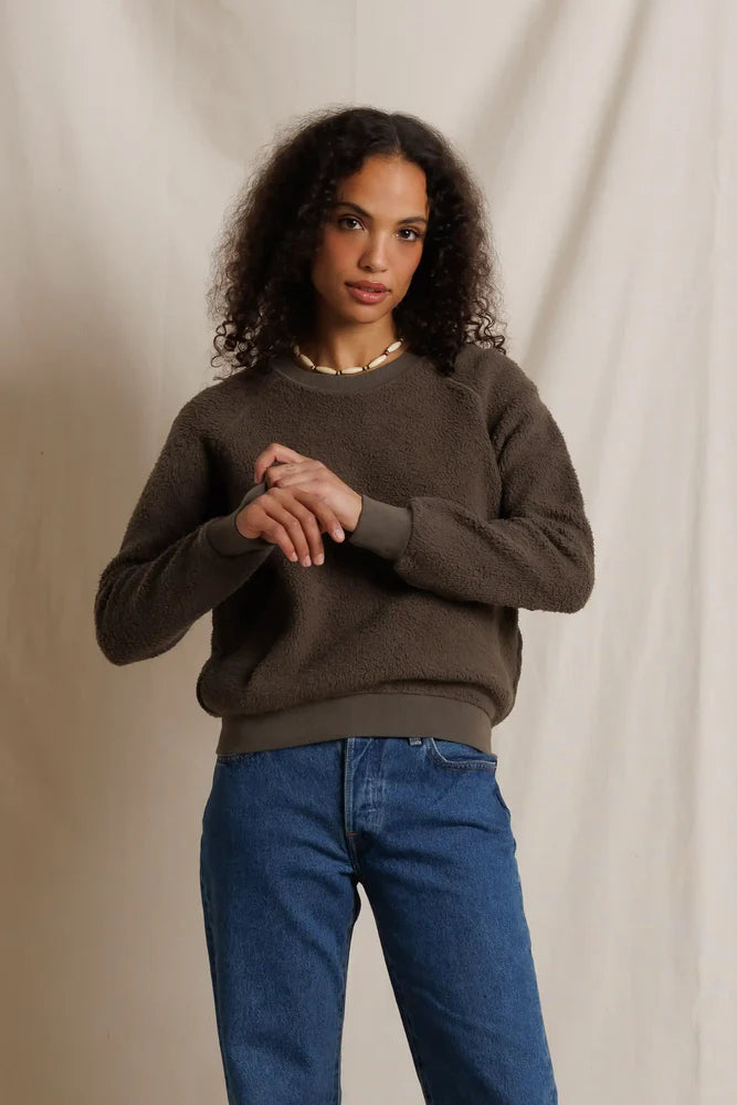 Perfectwhitetee Ziggy Reverse LS Sweatshirt in dark olive, worn by a woman standing before a beige curtain.